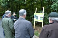 Mehrere Personen stehen im Wald vor einem Schild