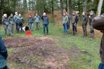 Gruppe von Personen im Halbkreis stehend, auf einer Waldlichtung