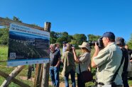 TeilnehmerInnen fotografieren die Infotafel am Rand einer Agroforstanlage