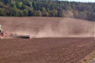 bei der Bodenbearbeitung zieht ene Staubwolke hinter dem Traktor und Maschinen her