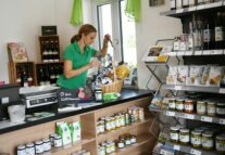 Landwirtin bestückt auf der Ladentheke des Hofladens einen Geschenkkorb
